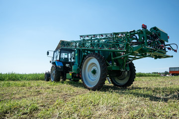 Fototapeta premium blue tractor in the field is preparing for chemical treatment of plants