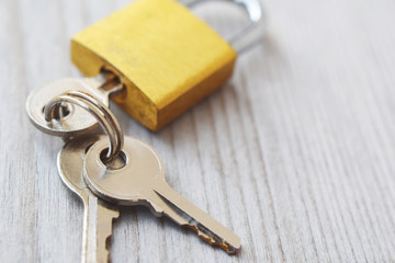 Golden padlock with three silver color keys on wooden background with copy space for text.