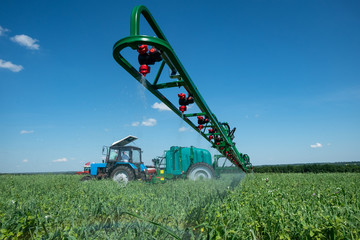 blue tractor in the field is preparing for chemical treatment of plants