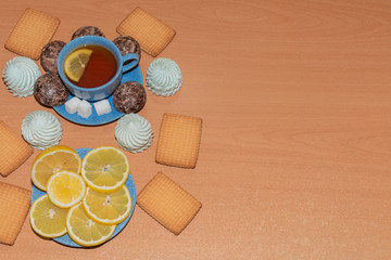 Lemon, marshmallow, gingerbread and cookies with a Cup of tea on a wooden background
