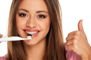 young woman holding electric tooth brush with black active charcoal toothpaste on white background...