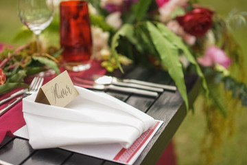 Naklejka na ściany i meble Napkin with personalized guest card on the table. Wedding dinner decor in burgundy swelling with the addition of green leaves