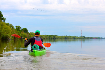 Man paddling in green kayak on a Danube river. Water tourism. Kayaking.