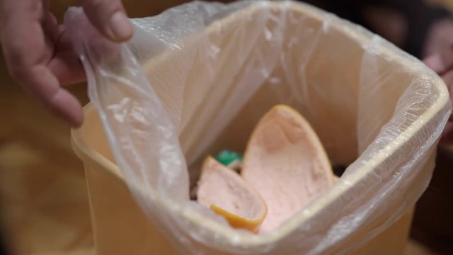 Removing full trash bag from small garbage can swing bin in the kitchen