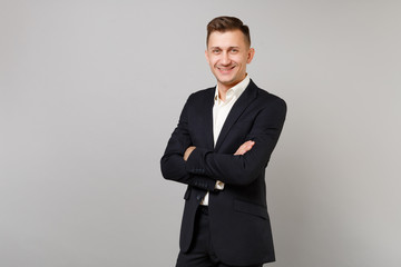Portrait of smiling young business man in classic black suit and shirt holding hands folded...