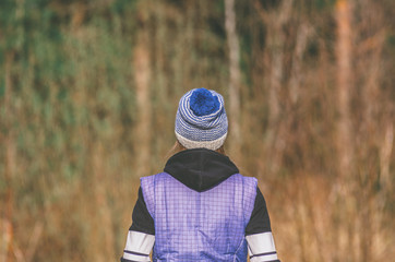 Woman in winter knitted hat with pompon back view on the background of nature