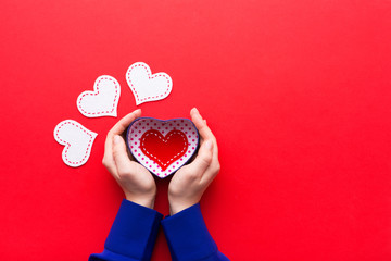 Person holding a present for Saint Valentine's day in his hands. Beautiful colorful background to st. Valentine day. Greeting card with red hearts. Wedding's invitation. Love expression. 