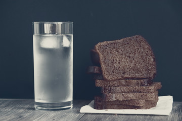 Black rye bread slices and glass of cold water. Concept of simple food and dieting.