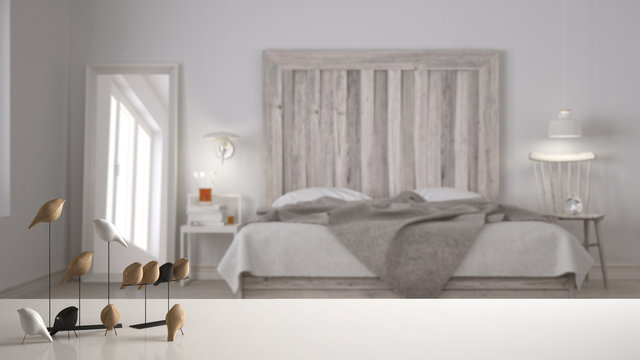 White table top or shelf with minimalistic bird ornament, birdie knick - knack over blurred scandinavian bedroom with wooden headboard, modern interior design
