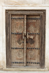 Carved wooden door and ornate doorway in a courtyard of traditional Arabian house of pearl trader Shaikh Isa bin Ali, Muharraq, Bahrain 