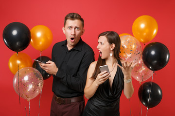 Couple stand back to back messaging in cellphone celebrating birthday holiday party isolated on red...