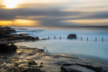 Sunrise at Mahon Ocean Pool, Sydney, Australia. Long exposure imageas the waves wash over the pool.
