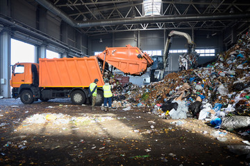 Two workers of recycling plant control process of unloading garbage from garbage truck