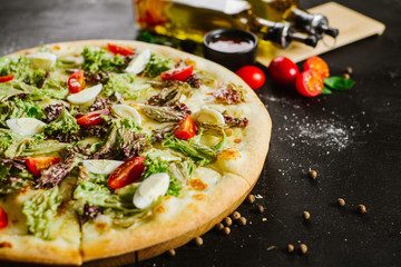 A vegeterian pizza withvagetables and herbs on black background
