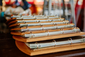 Multiple menu folders in a cafe or bar. Decorated on a wooden substrate with metal rings