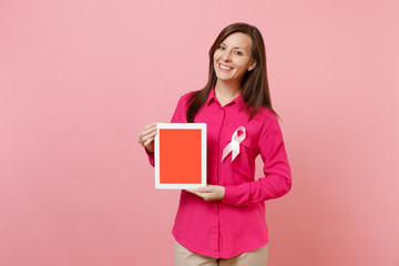 Woman in rose clothes with pink silk ribbon hold tablet pc isolated on pastel wall background, studio portrait. Medical healthcare gynecological oncology, Breast Cancer Awareness concept. Mock up area