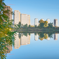 Fototapeta premium Beautiful cityscape in Kyiv, Ukraine. Reflection of trees and high buildings in the water.
