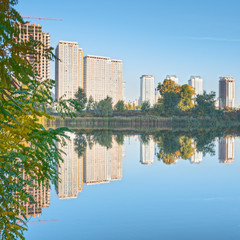 Beautiful cityscape in Kyiv, Ukraine. Reflection of trees and high buildings in the water.