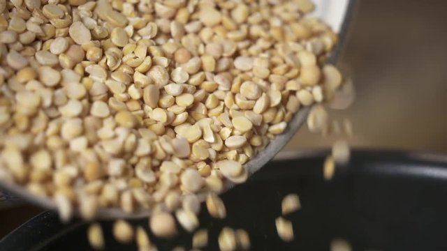 Cooking yellow split pea. Pouring split peas into the pot in slow motion.