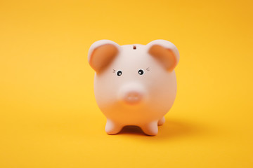 Close up photo of pink piggy money bank isolated on bright yellow wall background. Money accumulation, investment, banking or business services, wealth concept. Copy space advertising mock up.