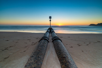 Sunrise over iconic Manly Beach, Sydney Australia. Clear skies and the storm water pipes lead the...