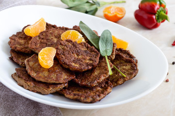 Tasty liver cutlets with tangerines on a white plate on the table.