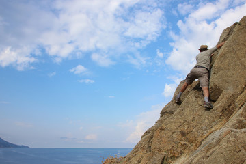 Man climbing on a rock in Elba island, Enfola headland, Italy
