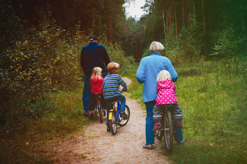 Naklejka premium active senior grandparents with kids riding bikes in nature