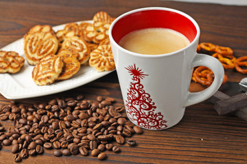 A cup of coffee, grains of coffee and cookies on a wooden table.