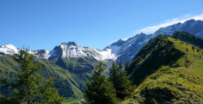 first snow fall on high green mountain peaks in the Alps of Switzerland with jagged ridges and deep green mountain valleys below