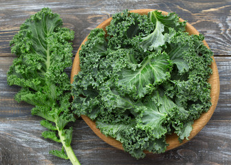 Fresh green curly kale leaves on a wooden table. selective focus. rustic style. healthy vegetarian food - obrazy, fototapety, plakaty