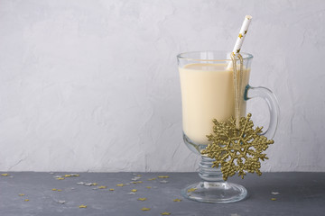 Homemade eggnog with thyme and orange in a glass on a gray background with Christmas decorations, free space, selective focus. Traditional winter Christmas drink