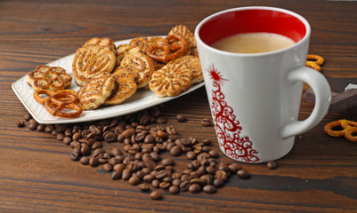 A cup of coffee, grains of coffee and cookies on a wooden table.