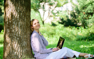 Obraz premium Minute for relax. Education technology and internet concept. Girl work with laptop in park sit on grass. Natural environment office. Work outdoors benefits. Woman with laptop work outdoors lean tree