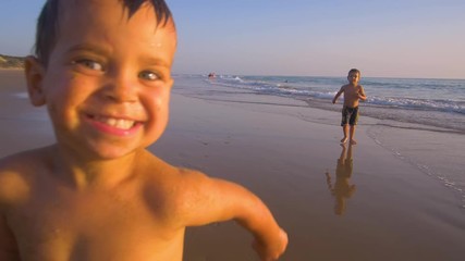 Slow motion - Two little brothers running, playing and enjoying while the camera chase them smiling and laughing