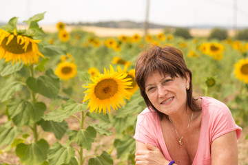 Obraz na płótnie Canvas Mature woman in a field of sunflowers