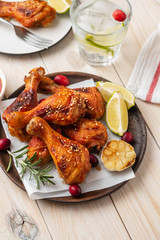 Tasty appetizing baked chicken legs served with spices, rosemary and cranberries on wooden background table. Christmas dish. Copy space.