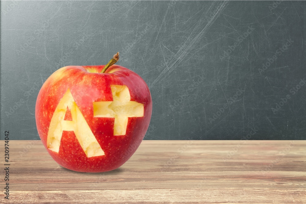 Wall mural photo of red apple with a+ on the school desk