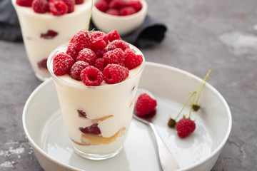 Tiramisu with raspberry in glasses on grey background. Italian dessert. Copy space.