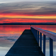 Sunset at Long Jetty, Central Coast. Pink, red glow and reflection as a bird looks on.