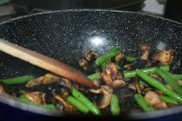 Fried champignons and green beans in a pan. Cooking process. Selective focus.
