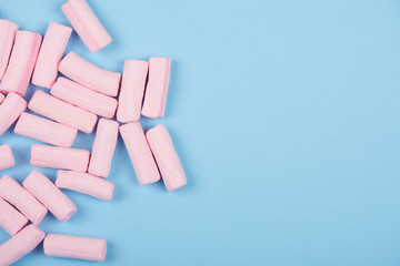 Pile of pastel pink marshmallows on a pastel blue background (top view with copy space on the right)