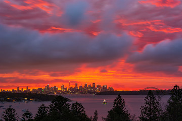 Obraz premium Sunrise over Sydney Harbour, Australia. Cityscape with epic sunset and yacht in the foreground.