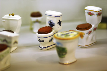 Collection of classic ceramic toilet bowls with wooden seat covers, souvenirs on display on shop shelf