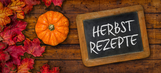 Herbstlaub mit Kürbis auf einem Holzbrett mit Tafel - Herbstrezepte