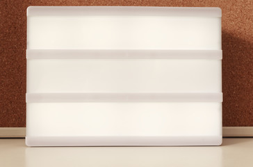 Luminous panel with three boxes for labeling with text in the background a cork pin board in a cool...