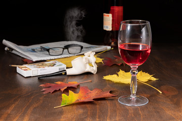 Weinglas mit Tabakpfeife und Tageszeitung bei Herbststimmung