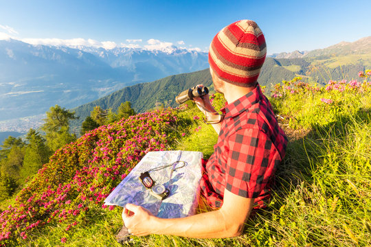 Hiker with map and binoculars looks towards Rhaetian Alps and Monte Disgrazia from Pizzo Berro, Bitto Valley, Lombardy