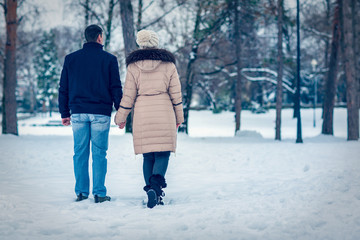 winter holiday - young couple having a walk in winter park.