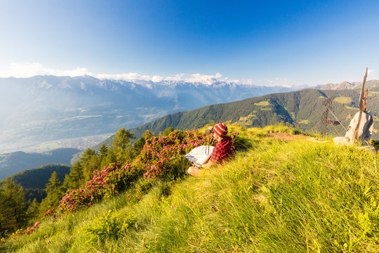 Hiker with binoculars and map looks towards Rhaetian Alps and Monte Disgrazia from Pizzo Berro, Bitto Valley, Lombardy